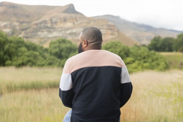 Black man sitting watching the mountains