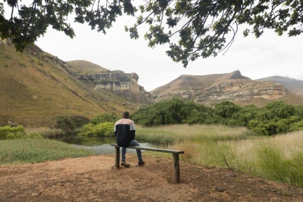 Black man sitting watching the mountains