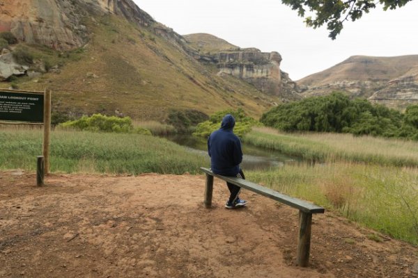 Black man sitting watching the mountains