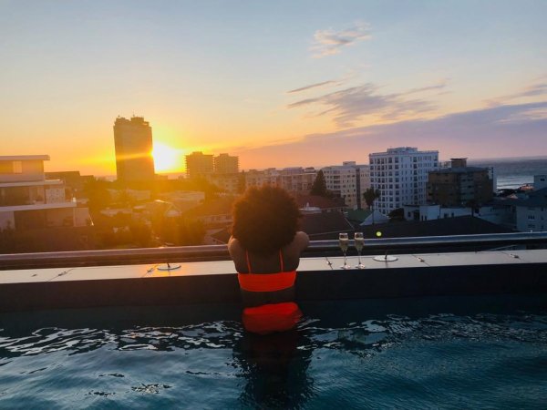 Black woman on a rooftop pool with a sunset