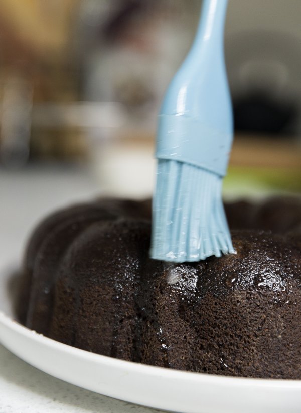 Coating a chocolate cake with a blue brush