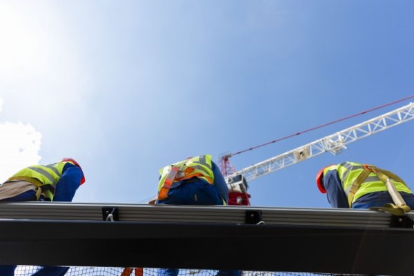 Black men in construction wearing safety belts