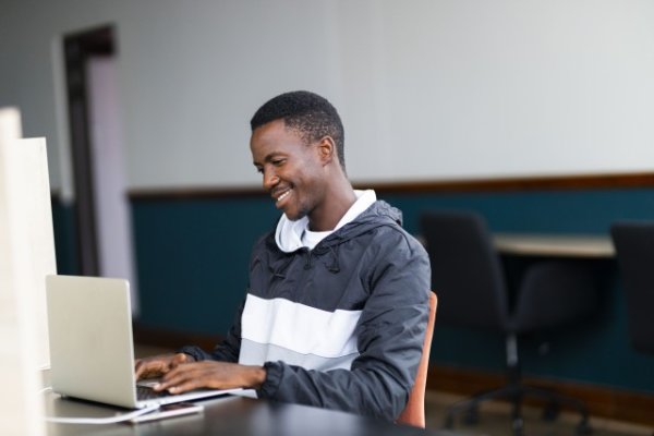 Black man looking at his laptop with a grin on his face
