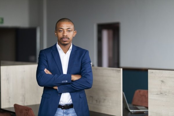 Black entrepreneur wearing a navy suit with folded arms