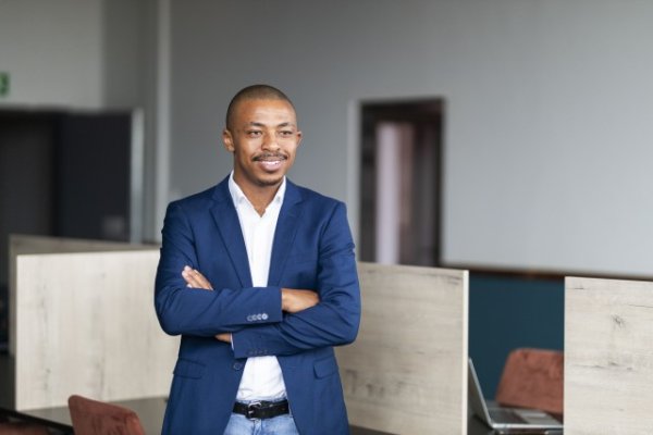 Black business man smiling with folded arms