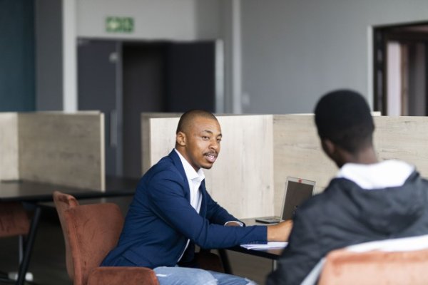 Black business man wearing a suit and talking to his client while smiling