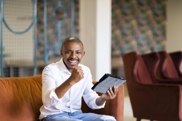 Black business man celebrating while looking at ipad