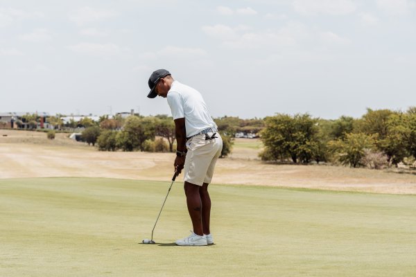 Black male golfer putting on the green