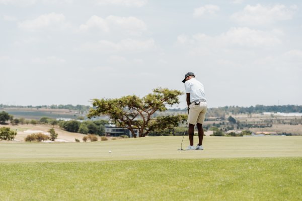 Black male golfer putting on the green with a view