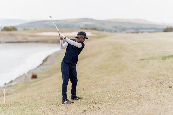 Black male golfer taking the perfect shot under pressure and near water