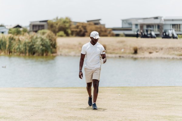 Black male golfer walking with a golf club in hand