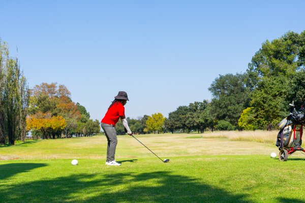 Black male golfer wearing a red golf shirt on the golf course