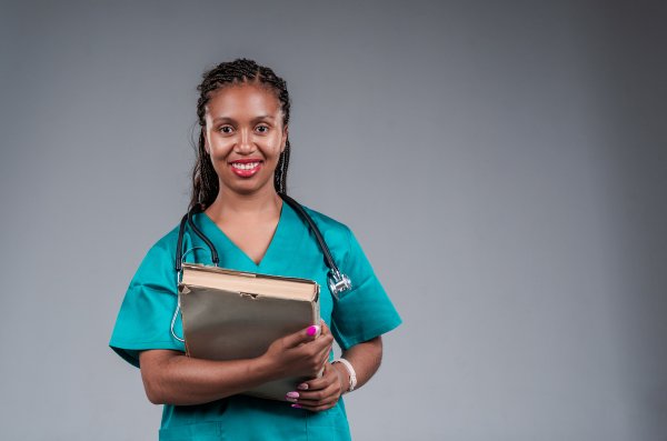 Female doctor smiling, with a stethoscope holding a book.