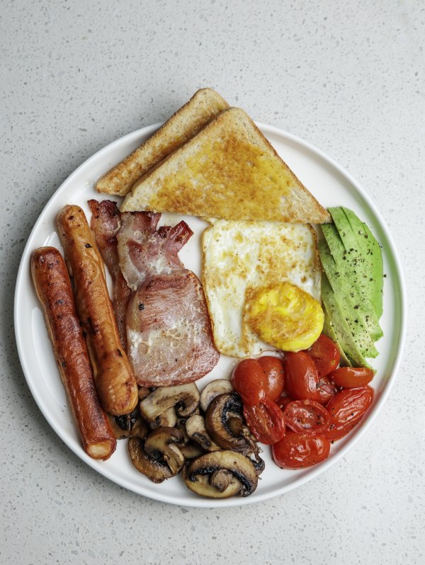 A South African breakfast with eggs, bacon, tomato, avocado, mushrooms and sausage