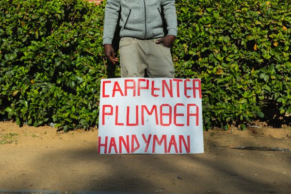 Jobless man with carpenter, plumber and handyman sign.