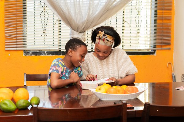 Mother and son reading the bible at home with fruits in the foreground.