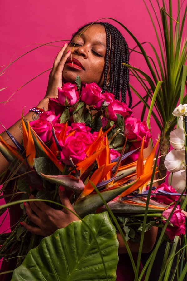 Black woman posing with pink backdrop and plants
