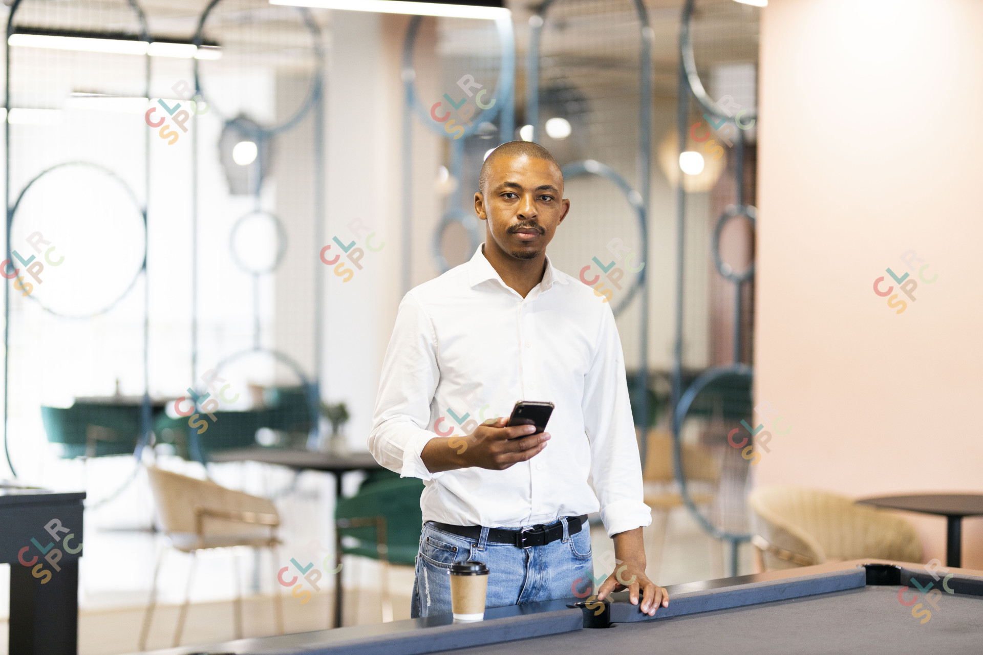 Black man on his cellphone by a pool table at work
