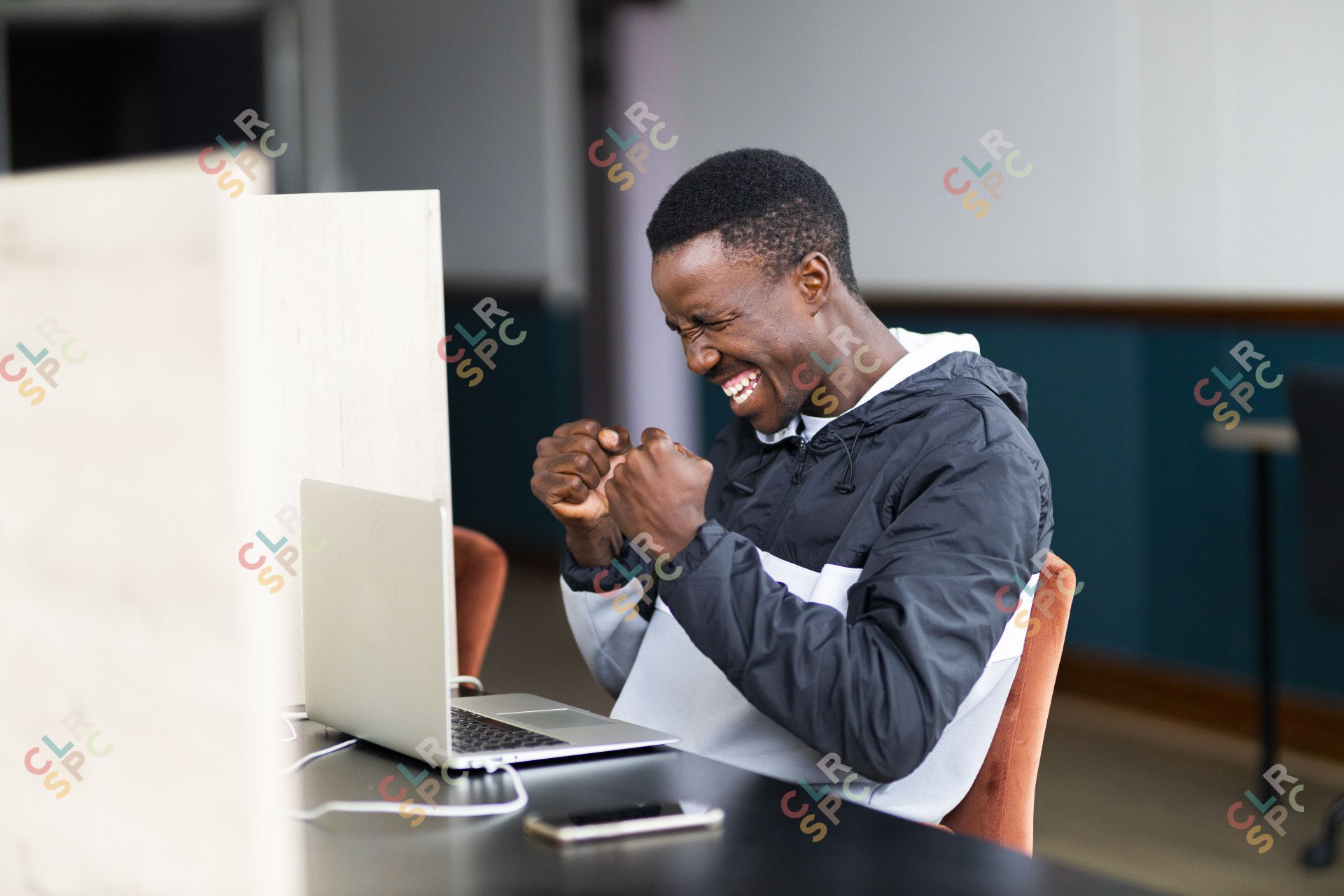 Black man celebrating a win and looking at his laptop