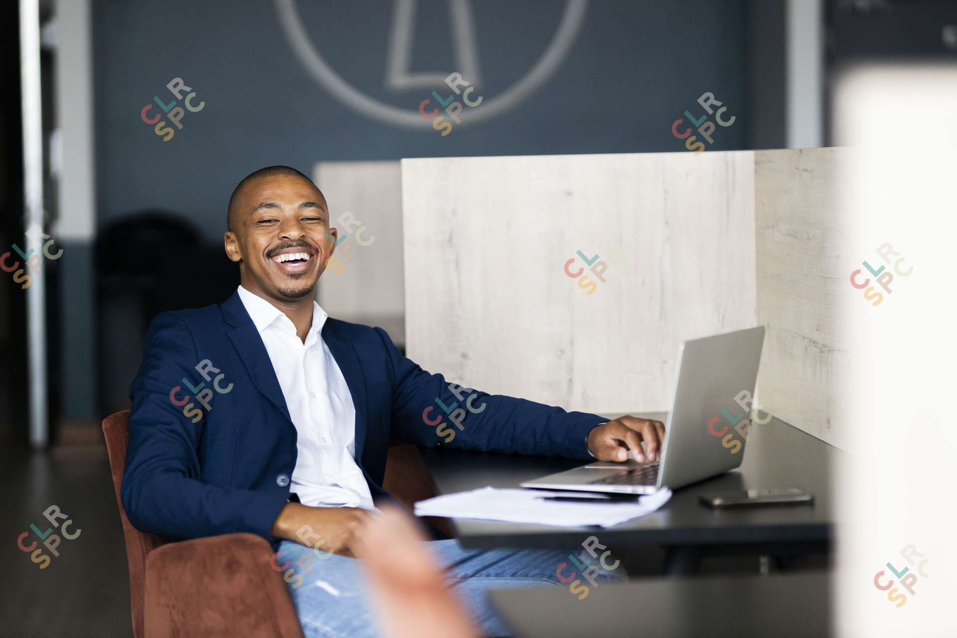 Black business man wearing a suit smiling at the camera at the office