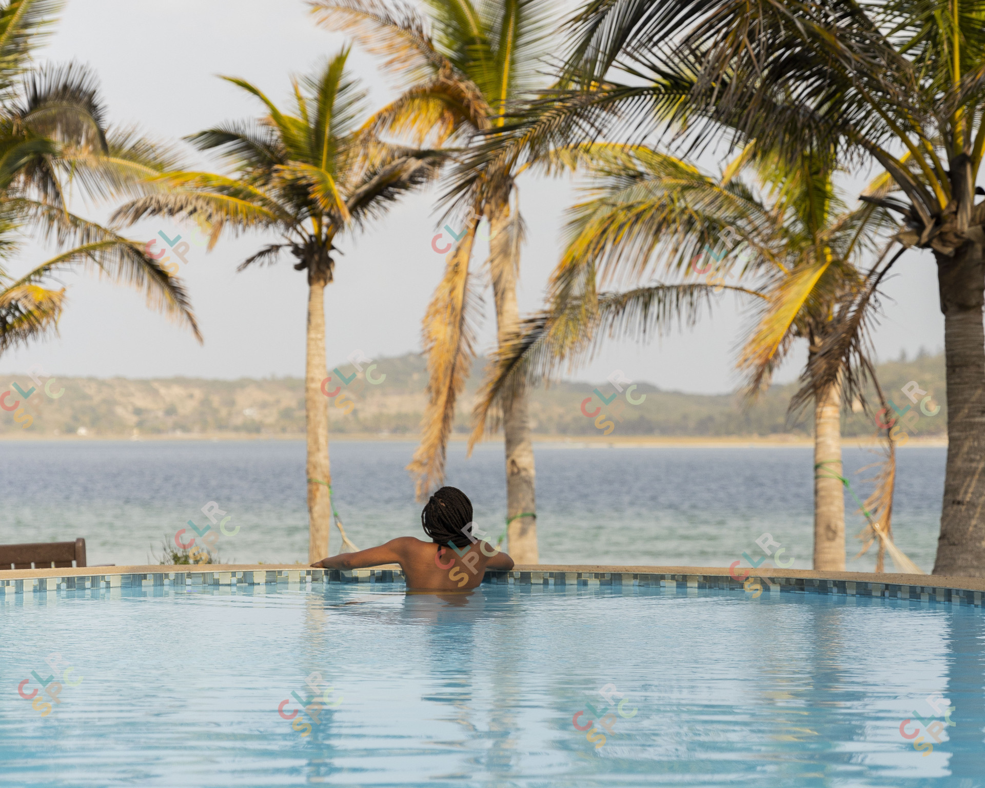 Black woman in a swimming pool overlooking a lagoon.