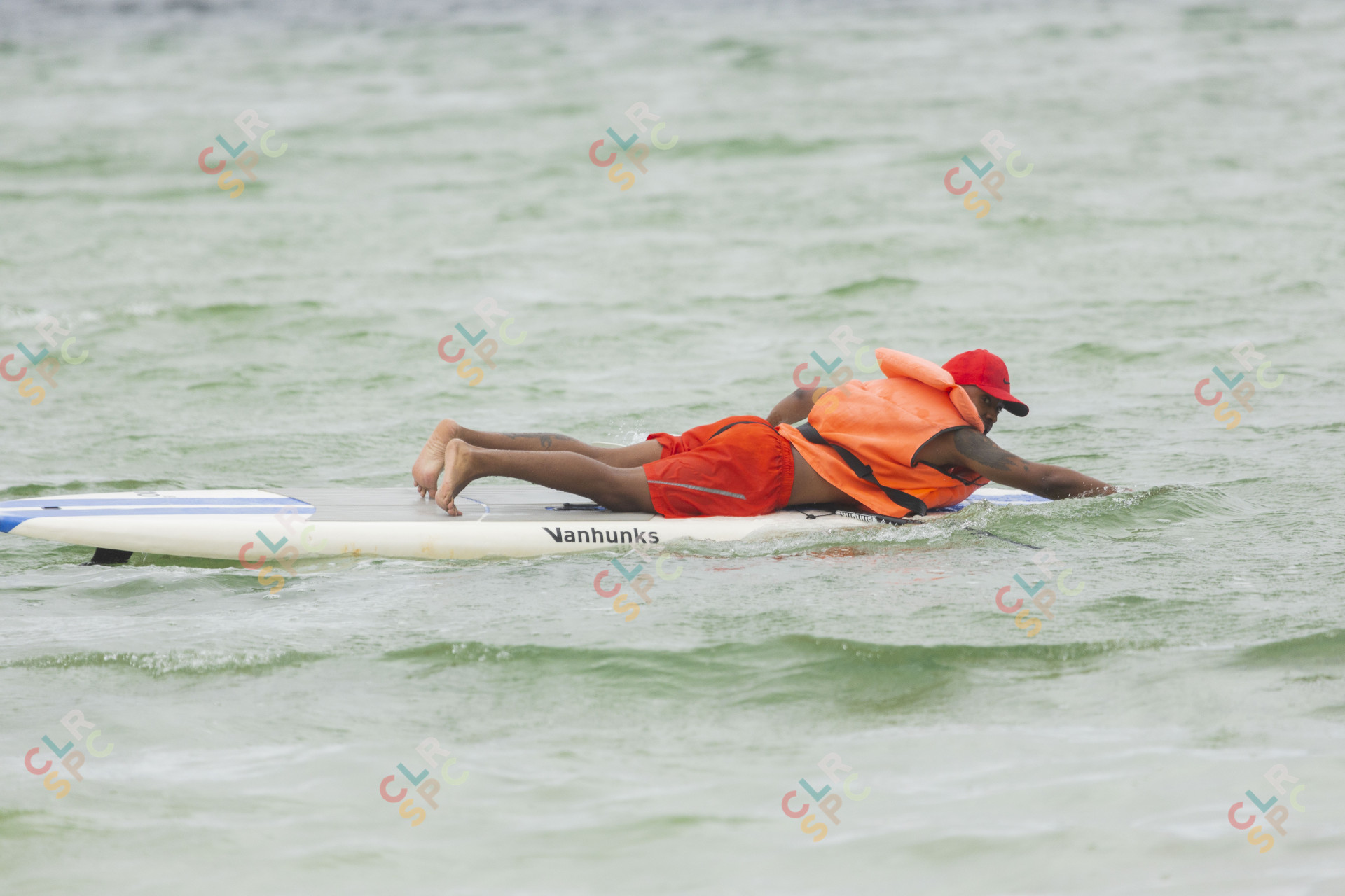 Black man on a surf board in a lagoon.