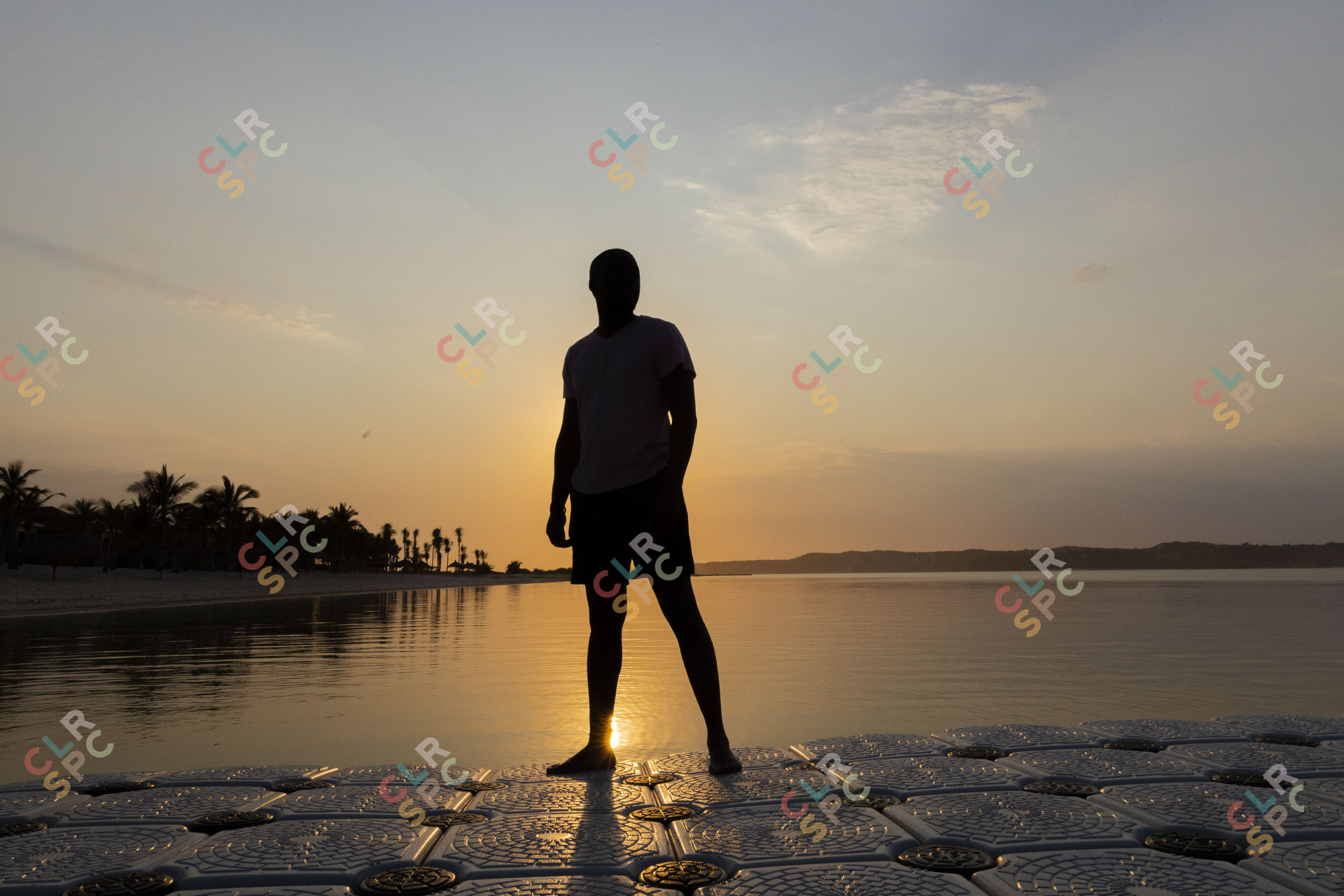Silhouette of black man near a lagoon of water.