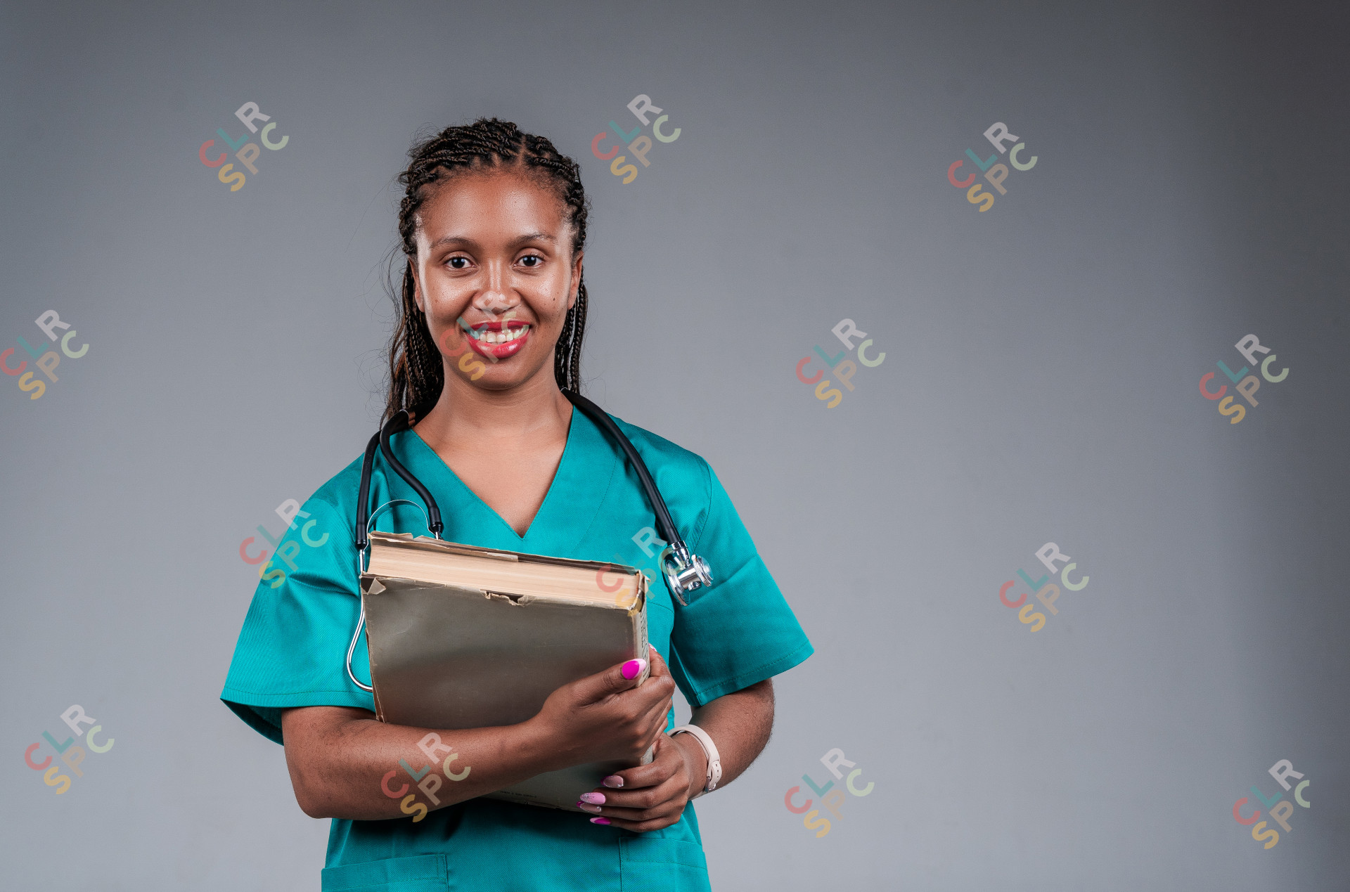 Female doctor smiling, with a stethoscope holding a book.