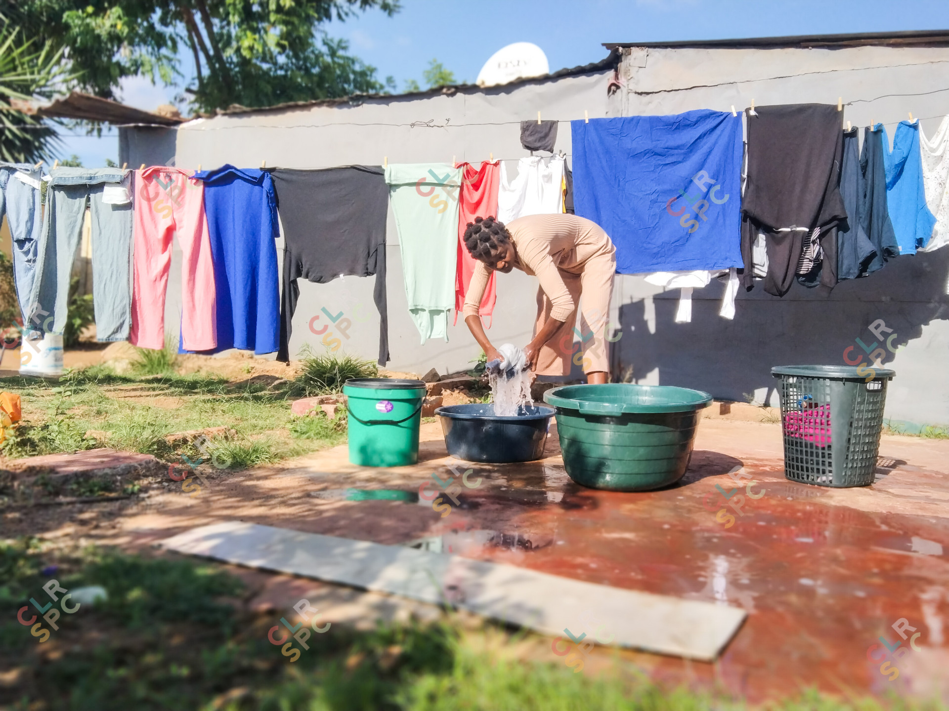Black woman washing clothes and hanging them outside.