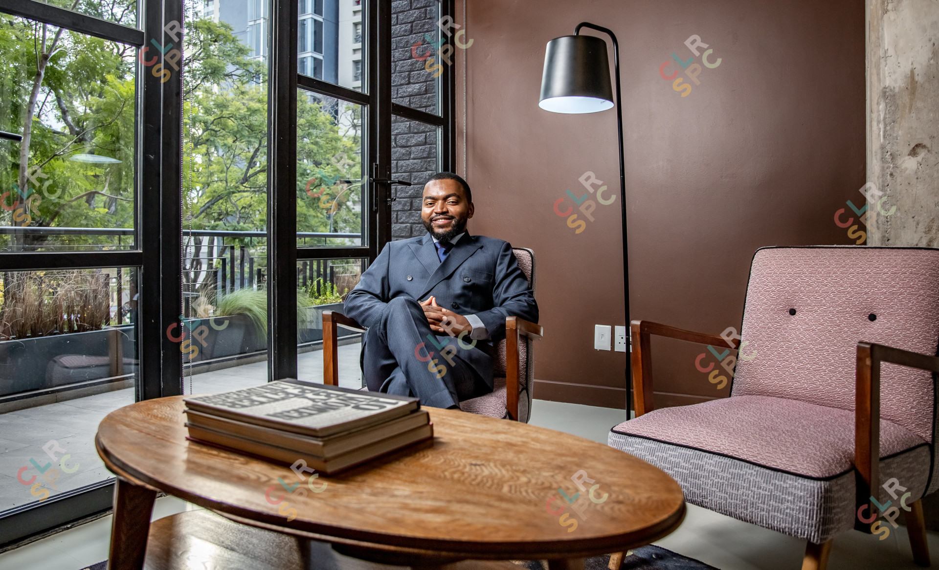 Corporate businessman sitting on a chair smiling with books on a table
