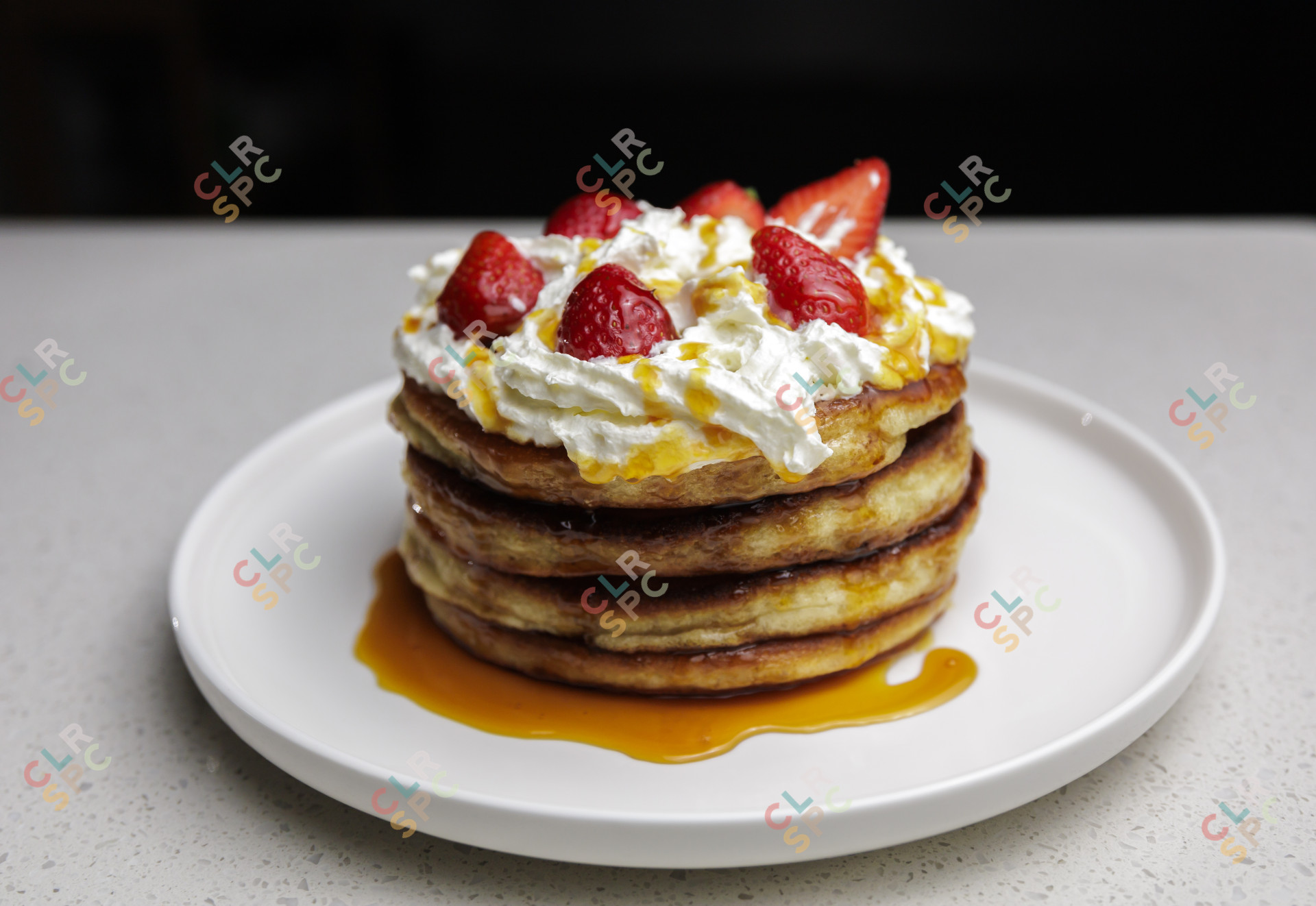 Well made pancakes with strawberries and cream on a white plate.