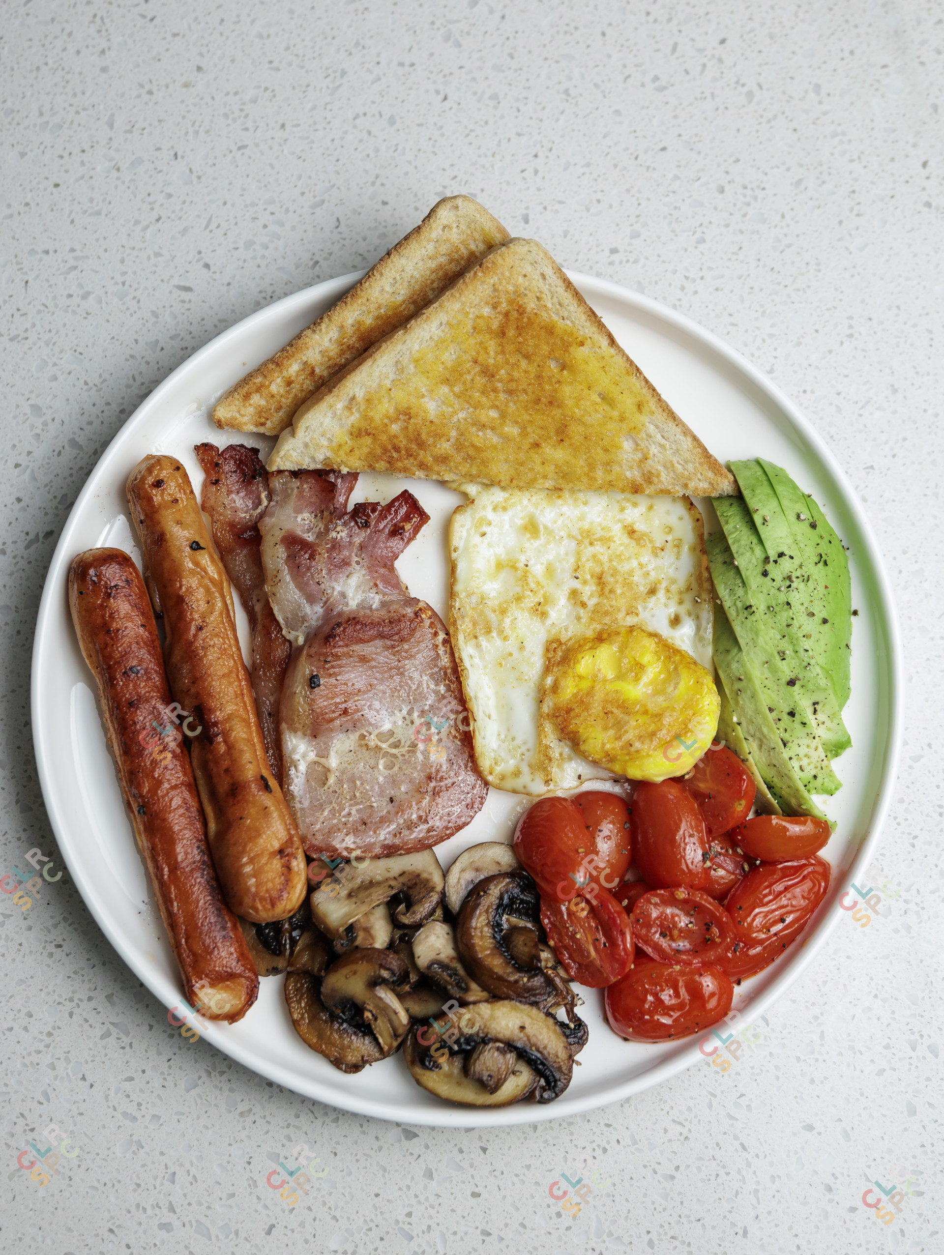 A South African breakfast with eggs, bacon, tomato, avocado, mushrooms and sausage