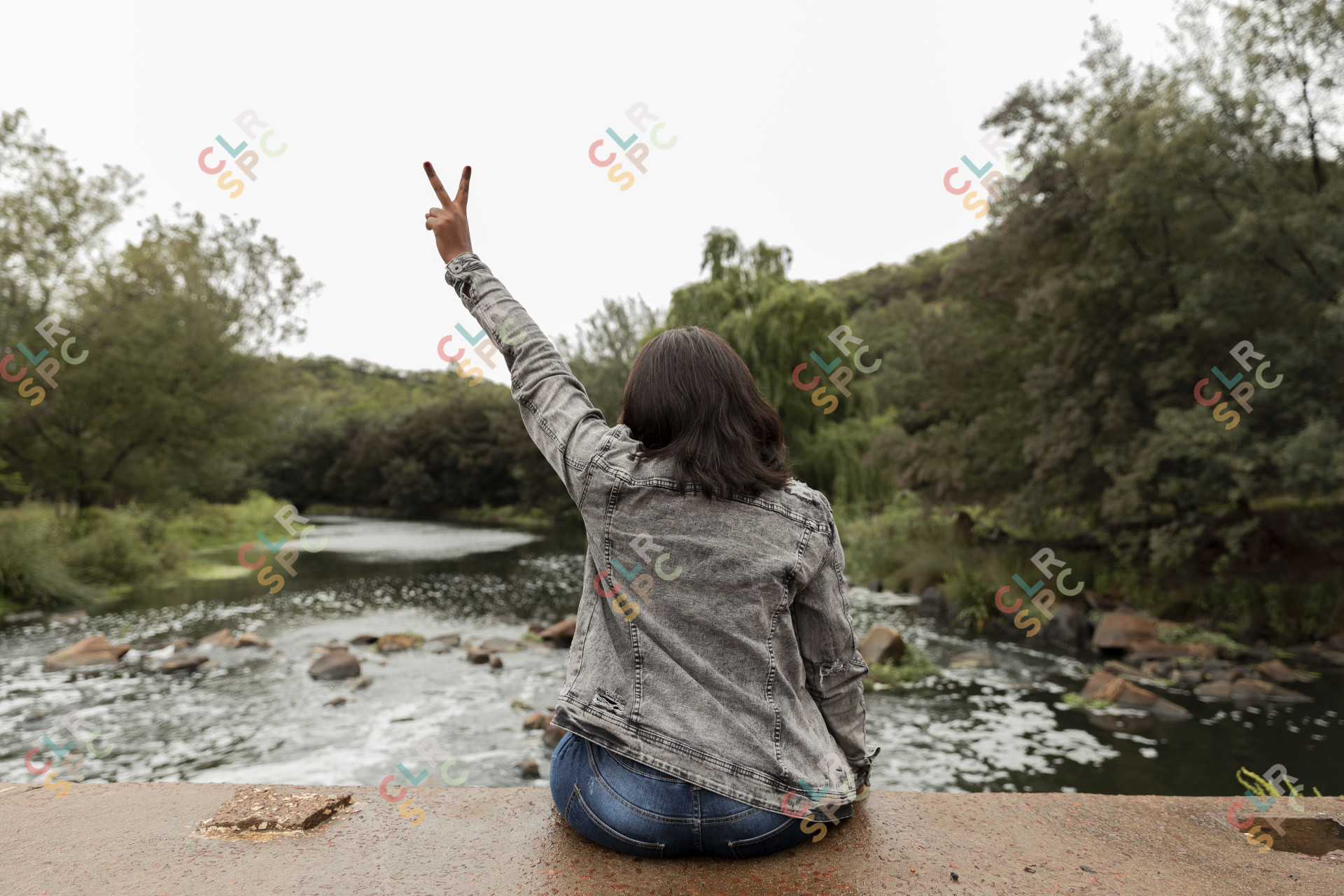 Black woman holding up peace sign by the river
