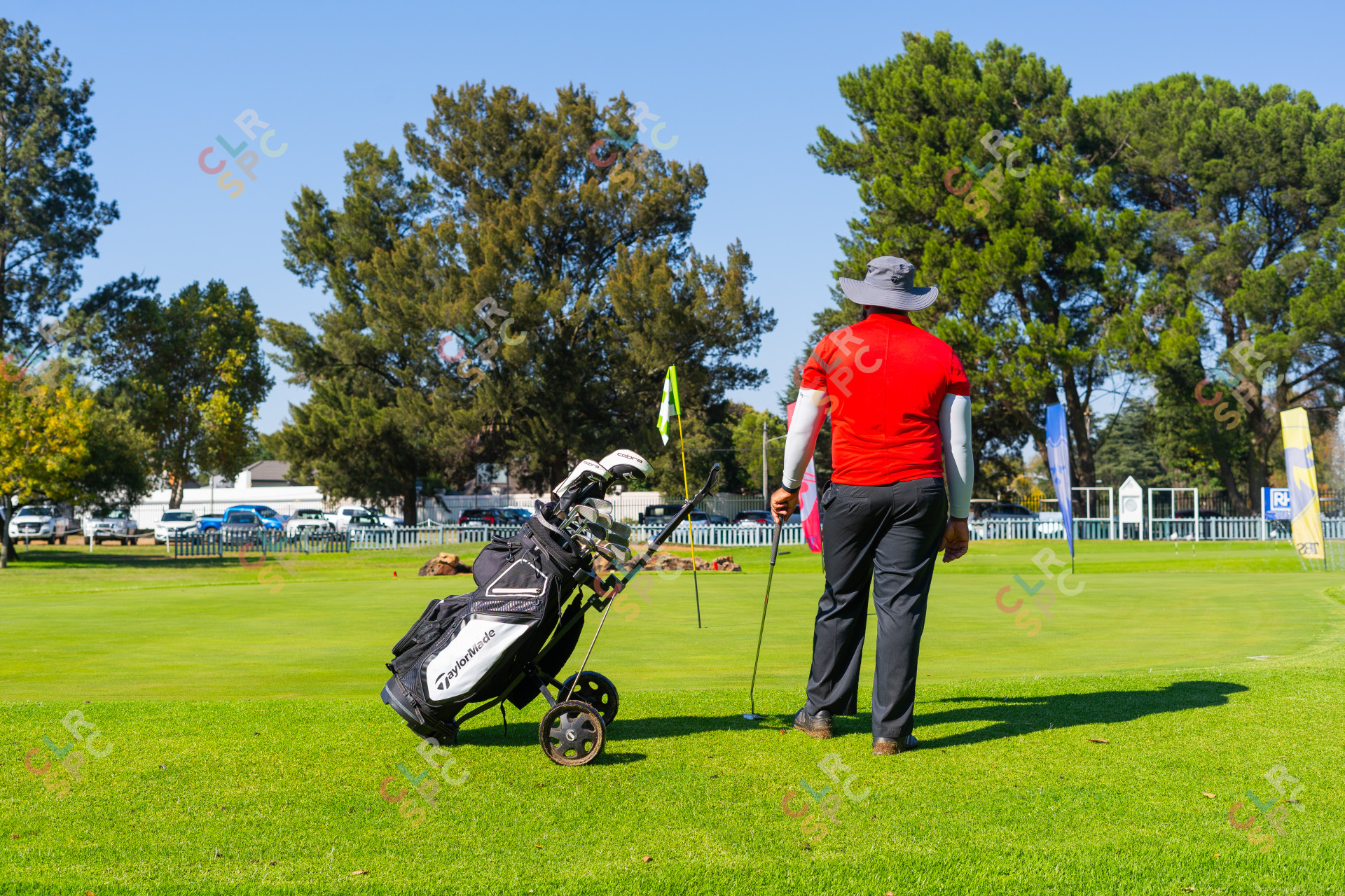 Black man wearing a red golf shirt with a Taylormade bag