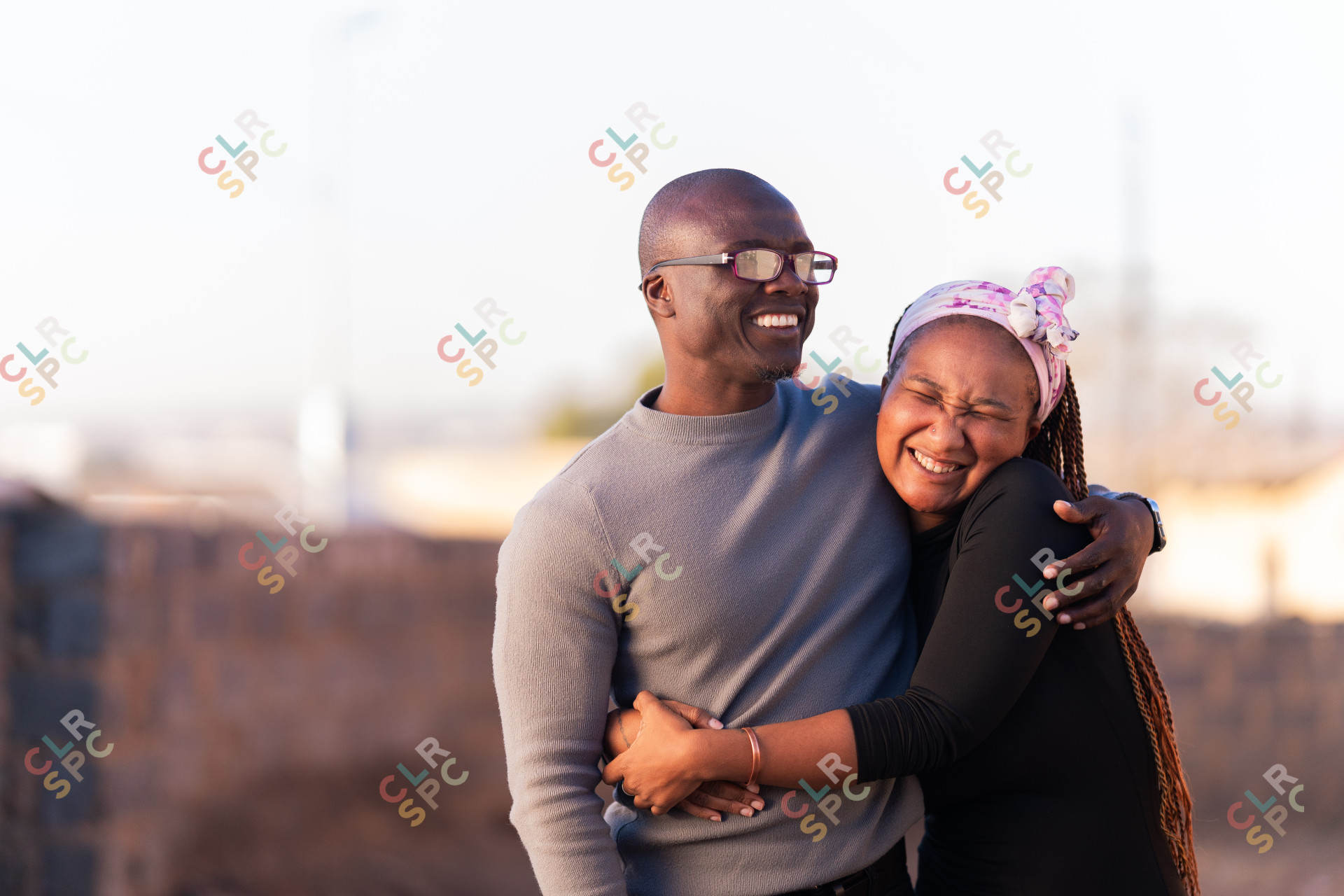 Black couple smiling outdoors with a blurred background of Alexandra.