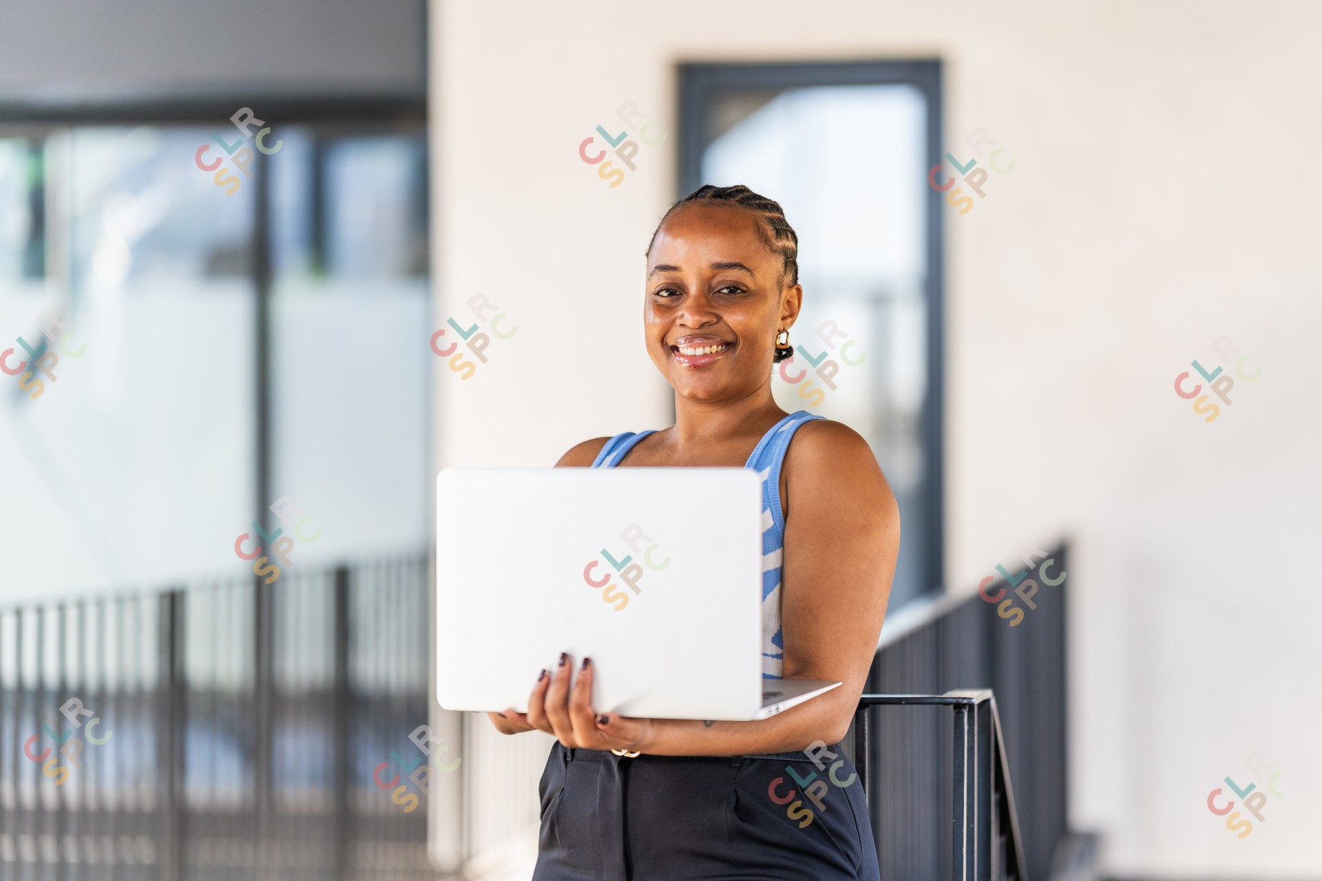 Close up photo of young corporate black woman holding laptop at work while smiling.