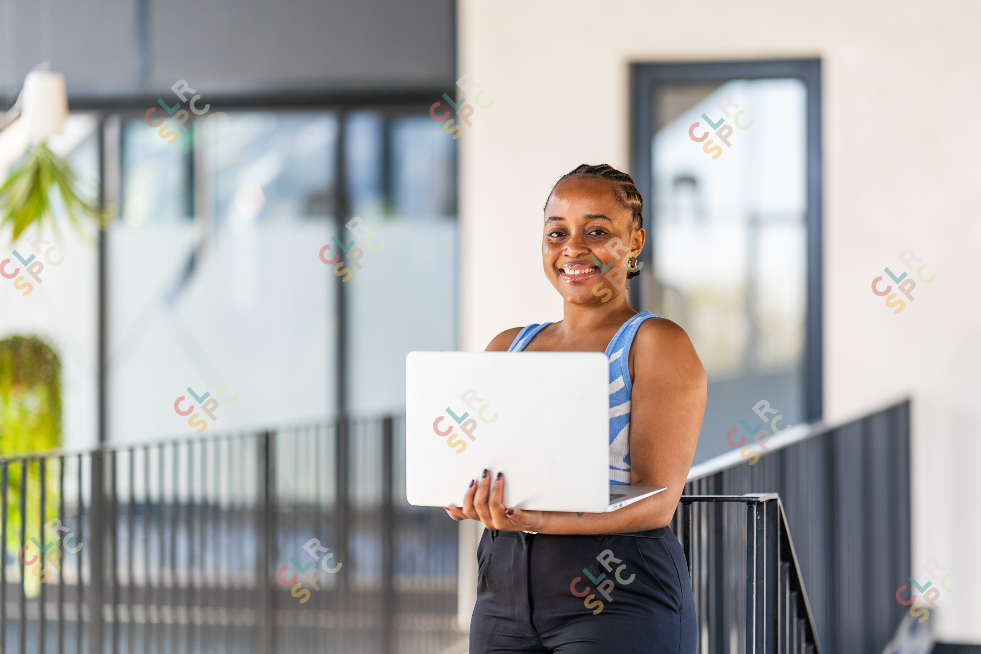 Portrait of a cheerful businesswoman in modern office and looking at camera. Smiling African executive using laptop while working from office.