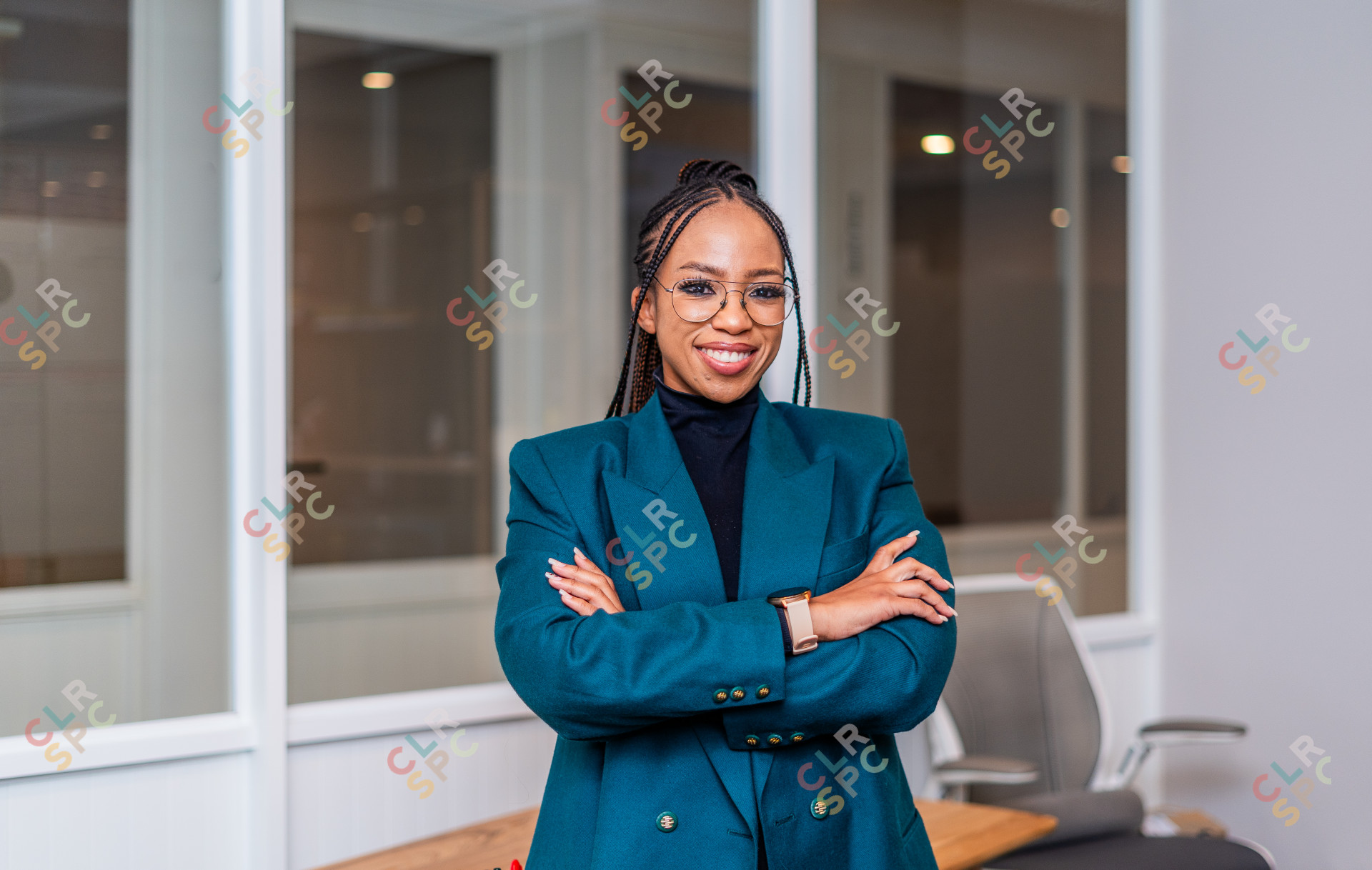 Young African business woman smiling at the office wearing a green jacket and glasses.