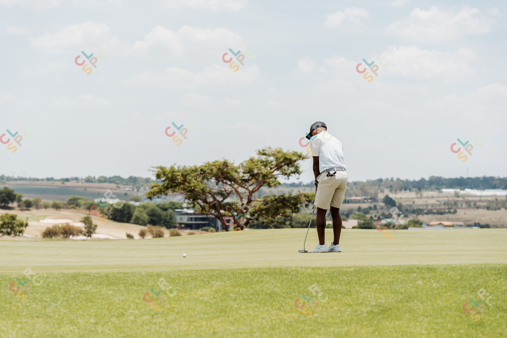 Black male golfer putting on the green with a view