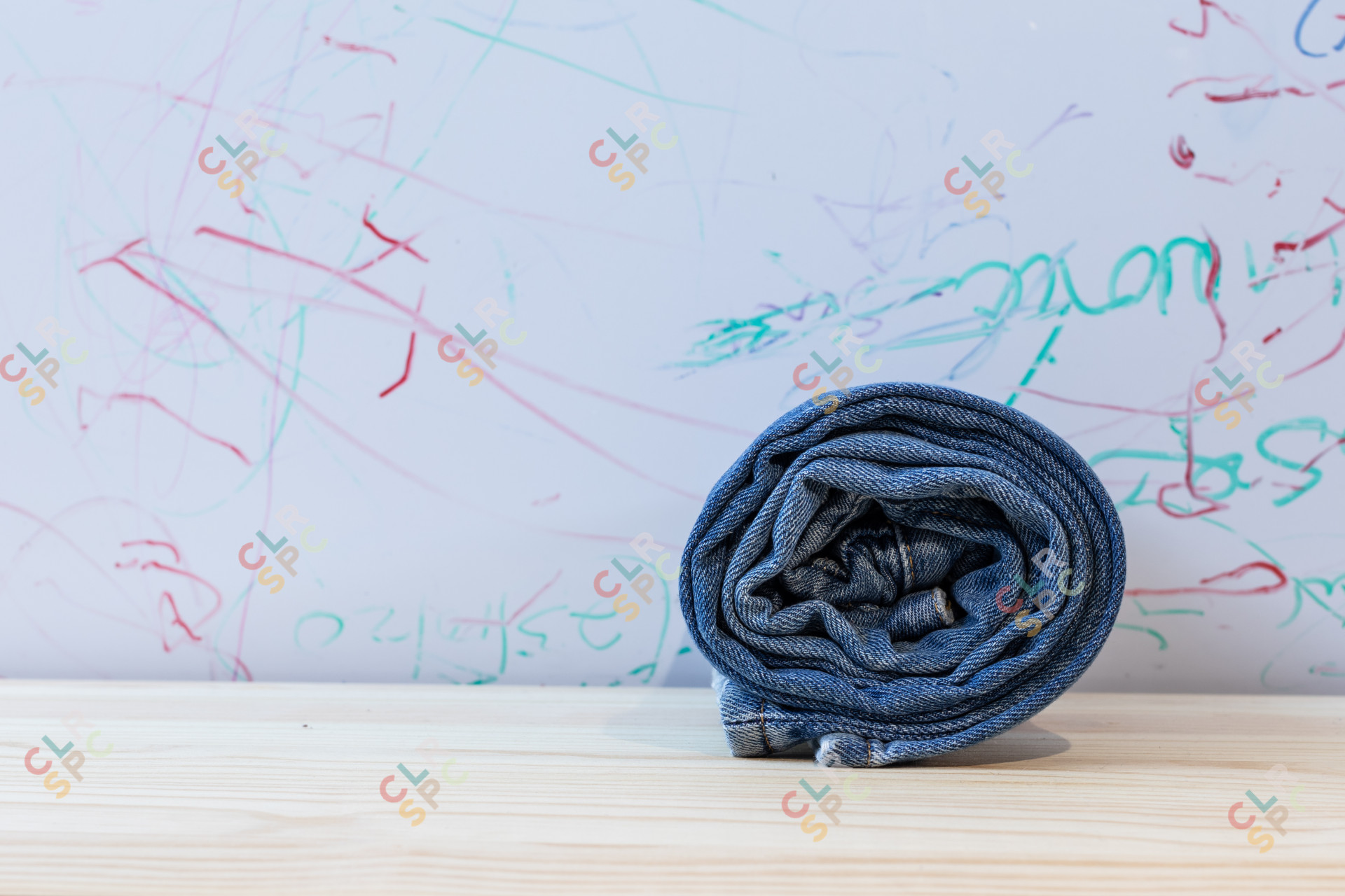A pair of rolled jeans on a wooden table with graffiti background