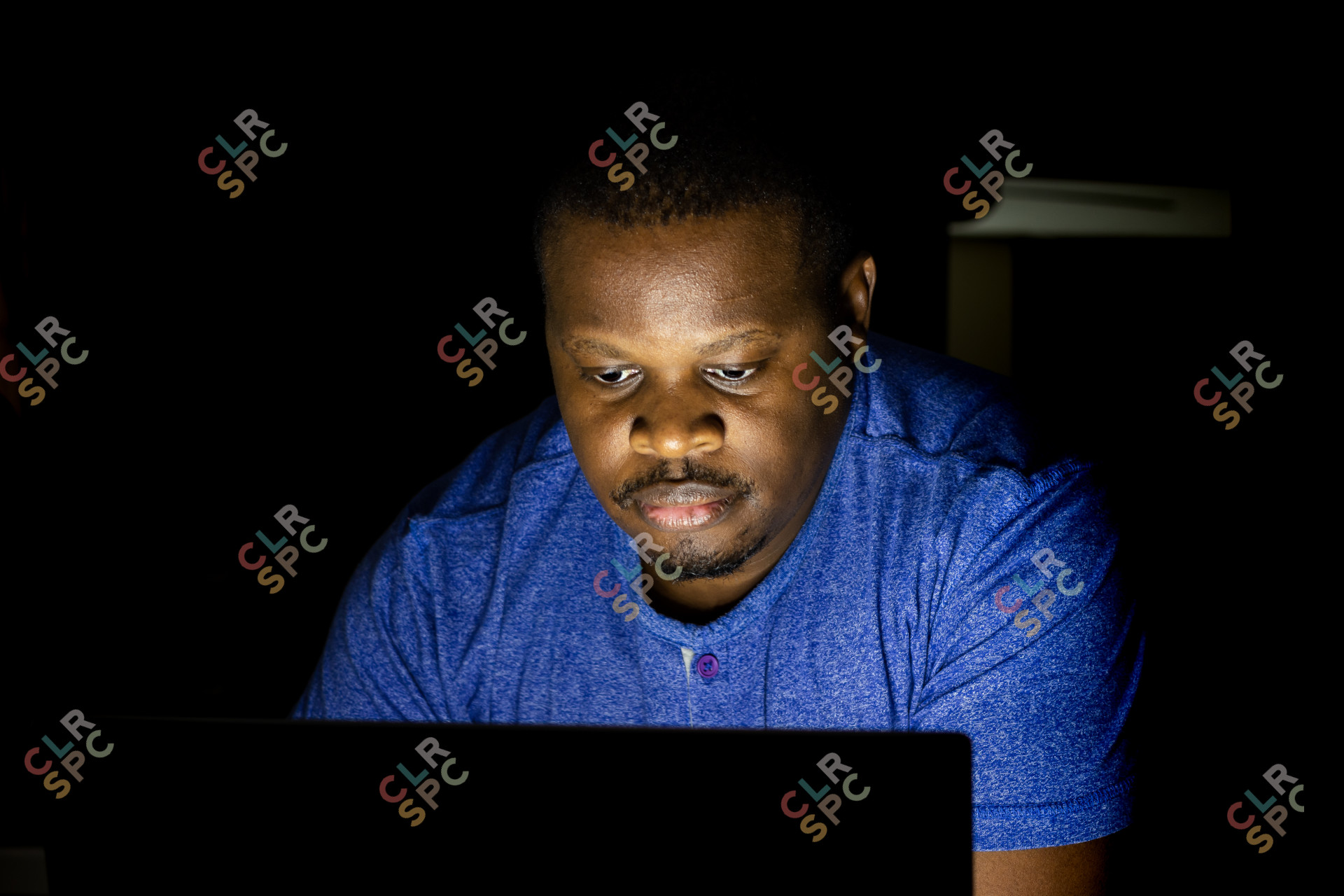 African male looking at laptop screen in the dark
