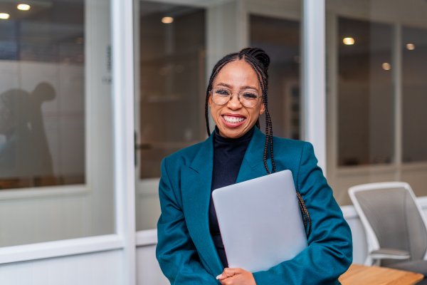 Young African Business woman holding a laptop smiling at the office.